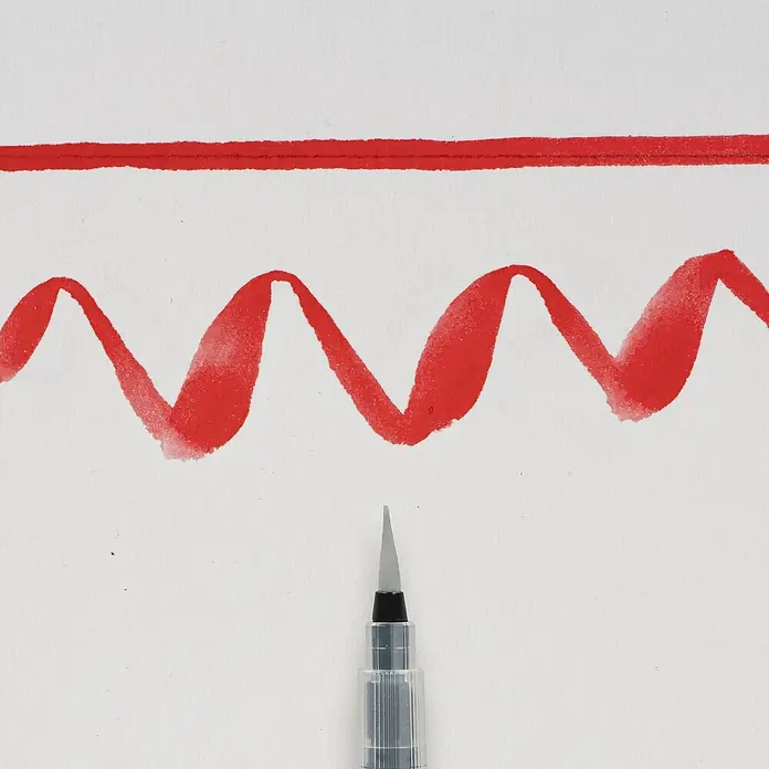 Talens Sakura Pincel artístico Koi - Tamaño pincel: Medio, Fibra sintética, Plástico - Primer plano de un pincel de acuarela con trazos rojos sobre papel blanco, ideal para proyectos artísticos y diseño creativo.