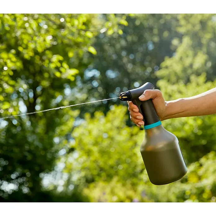 Gardena Handsprüher - Schwarz, 0,75 l - Nahaufnahme einer Person, die eine grüne Sprühflasche mit blauem Akzent gegen einen grünen, verschwommenen Hintergrund hält.