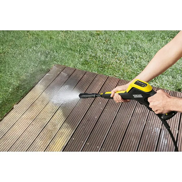 Kärcher Hidrolimpiadora de alta presión K5 Power Control - 145 bar, 2.100 W, Capacidad de bombeo: 500 l/h - Hidrolimpiadora Kärcher en uso sobre una terraza de madera para eliminar suciedad y escombros, refrescando la superficie.