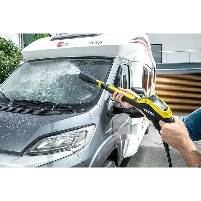 Kärcher Hidrolimpiadora de alta presión K7 Smart Control - 180 bar, 3.000 W, Capacidad de bombeo: 600 l/h - Una autocaravana está siendo limpiada con una hidrolimpiadora amarilla Kärcher, rociando agua en el parabrisas.