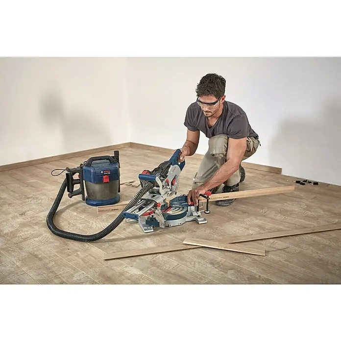Bosch Professional AMPShare 18V Akku-Kapp- & Gehrungssäge 18V-216 Solo - 18 V, Ohne Akku, Durchmesser Sägeblatt: 216 mm - Ein Handwerker benutzt eine Bosch Kapp- und Gehrungssäge mit Staubabsaugung, um Holzarbeiten durchzuführen. Schutzbrille ist wichtig!