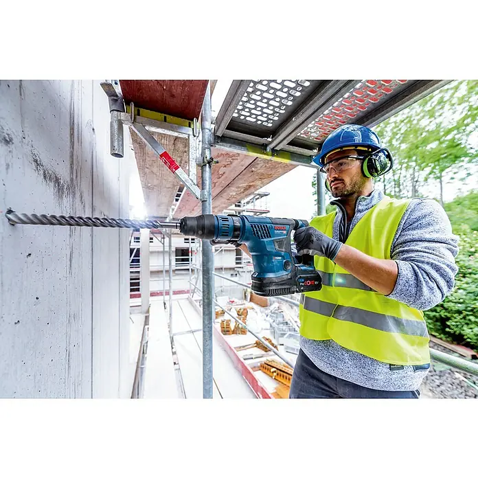 Bosch Professional AMPShare 18V Akku-Kombihammer GBH 18V-36 C - 18 V, Ohne Akku, 7 J - Ein Bauarbeiter bohrt mit einer Bosch Akku-Bohrmaschine ein Loch in eine Betonwand. Schutzhelm und Warnweste sind getragen.