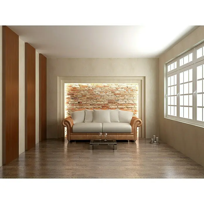 Rodapié Arica - 2,2 m x 13 mm x 90 mm - Elegante salón con sofá beige, pared de ladrillo destacada y grandes ventanas que crean un ambiente luminoso. El suelo de madera brillante completa el aspecto.