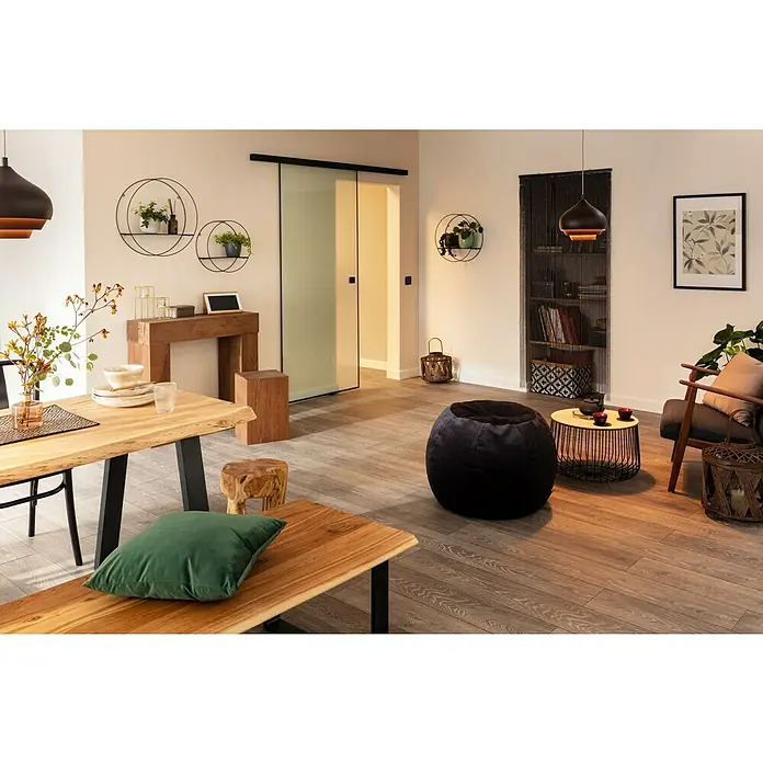 A.S. Création Vliestapete - Beige, Uni, 10,05 x 0,53 m - Einladendes Wohnzimmer mit Holztisch, Bank und stilvollen Dekoelementen, die eine warme Atmosphäre schaffen.