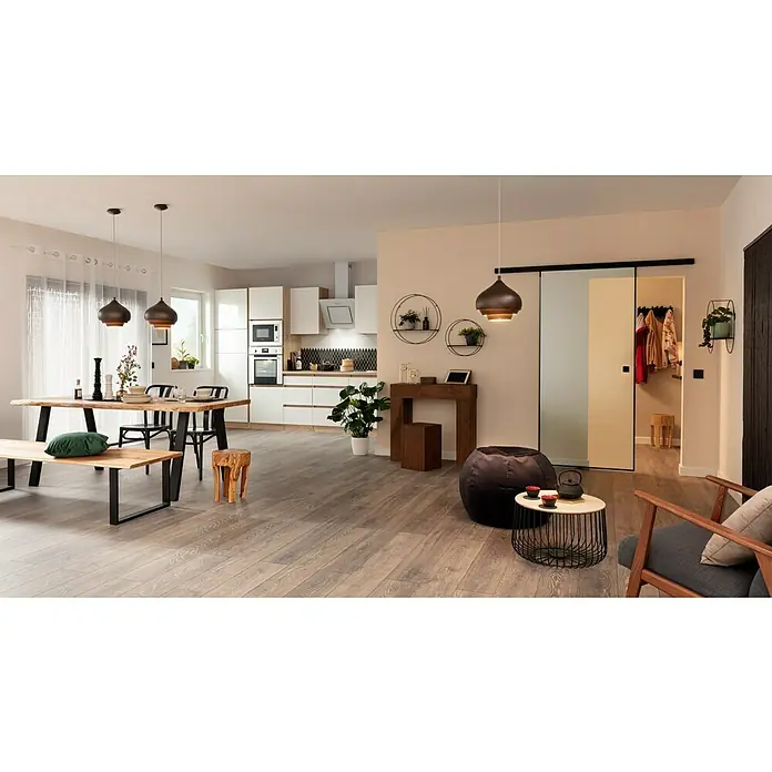 A.S. Création Vliestapete - Beige, Uni, 10,05 x 0,53 m - Wohnraum mit Holztisch und passender Bank, ergänzt durch Pendelleuchten. Die Küche im Hintergrund bietet Stauraum, während der Wohnbereich zum Entspannen einlädt.