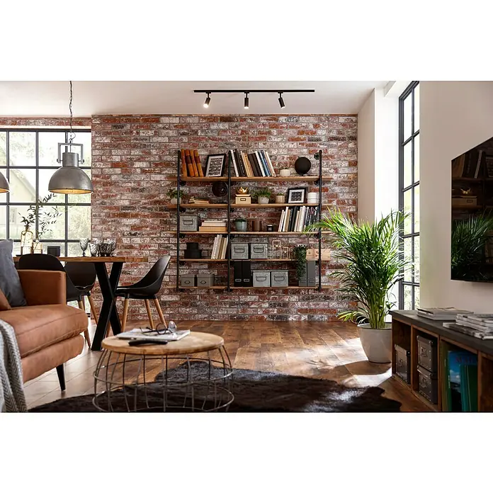 swingcolor Wandfarbe SIMPLYGreige - Nr. 08, 2,5 l - Wohnzimmer mit einem stilvollen Bücherregal mit Holzregalen und schwarzen Metallrohren an einer Backsteinmauer.