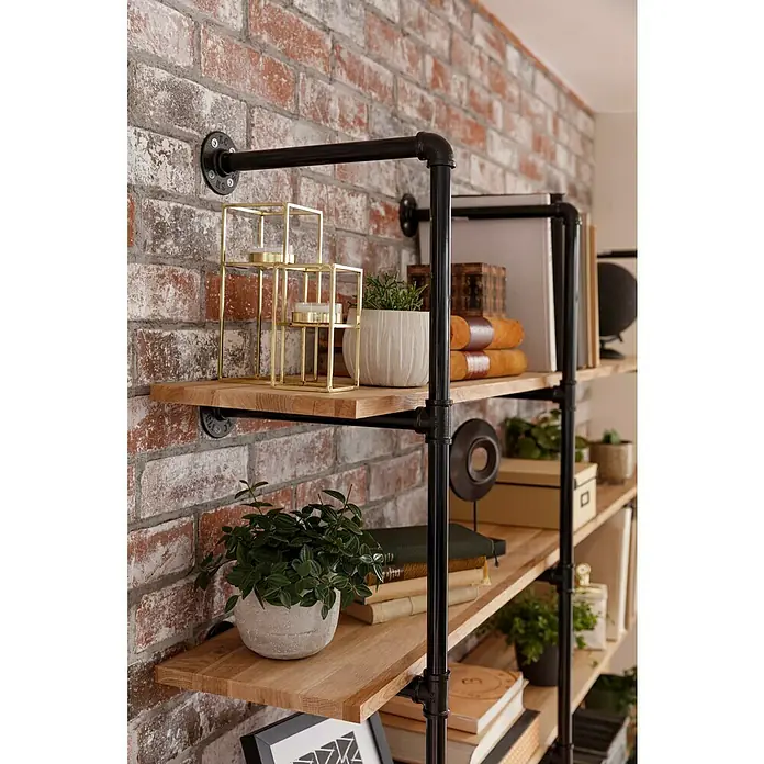 Celina Klinker Verblendstein Vintage New York7,1 x 24 cm, Braun/Rot, Steinoptik - Regal im Industrial-Stil mit Holzregalen und schwarzen Metallrohrstützen, dekoriert mit Pflanzen, Büchern und dekorativen Gegenständen vor einer Ziegelwand.