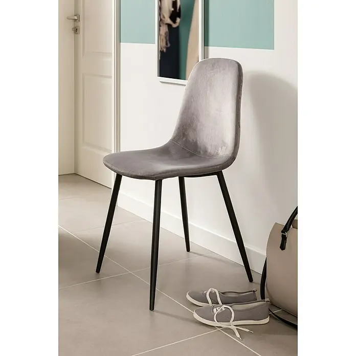 Art-Tec by Palazzo Feinsteinzeugfliese - 60 x 60 cm, Steel, Matt - Ein grauer Polsterstuhl mit schwarzen Beinen steht auf einem gefliesten Boden, daneben Schuhe und eine Tasche.