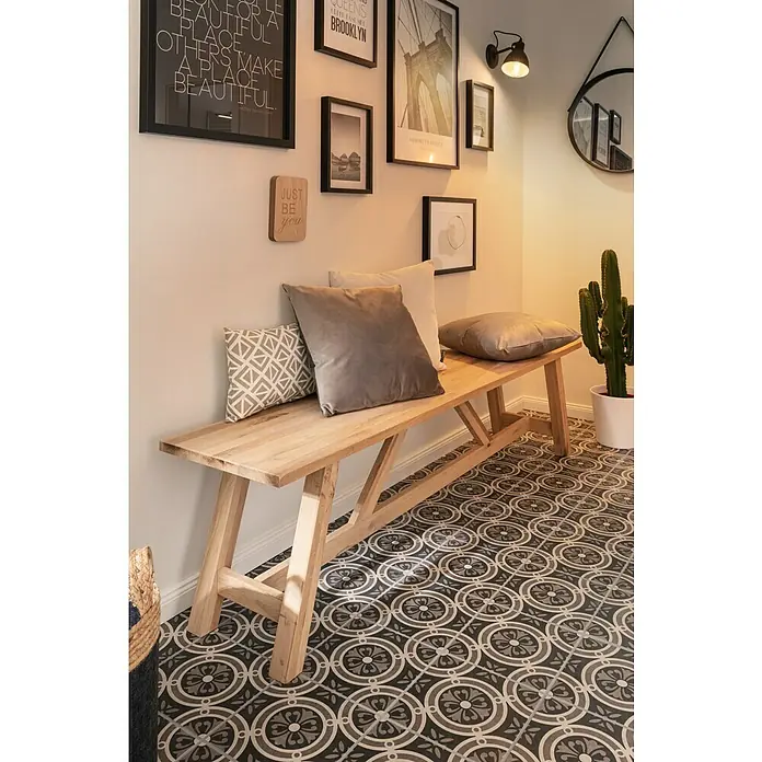 Feinsteinzeugfliese Vintage Classic25 x 25 cm, Schwarz/Grau/Weiß, Matt - Eine helle Holzbank mit Kissen vor einer Wand mit Bildern. Die Bank bietet Sitzgelegenheiten und Ablagefläche, die Kissen sorgen für Komfort.