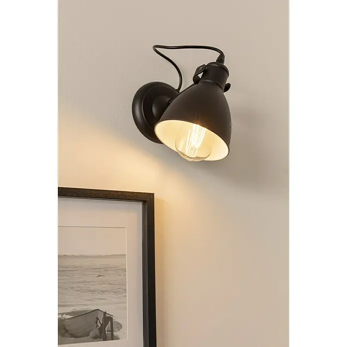 Eglo Priddy Wandleuchte - 40 W, Schwarz, Schwarz, Weiß, E27 - Nahaufnahme einer braunen Wandleuchte mit verstellbarem Schirm und einer dekorativen Glühbirne, die ein warmes Licht auf eine Wand wirft.