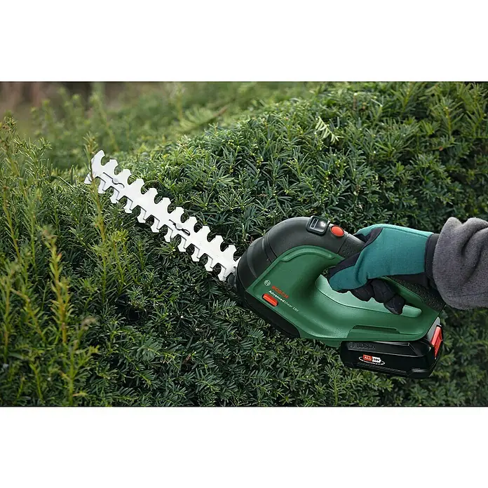 Bosch Power for All 18V Akku-Gras- & Strauchschere AdvancedShear 18V-10 - 18 V, Li-Ionen, 1 Akku, Schwertbreite: 10 cm - Eine Bosch AdvancedShear 18V Akku-Heckenschere schneidet eine dichte Hecke. Das Gerät ist grün-schwarz und wird mit einer Hand bedient.