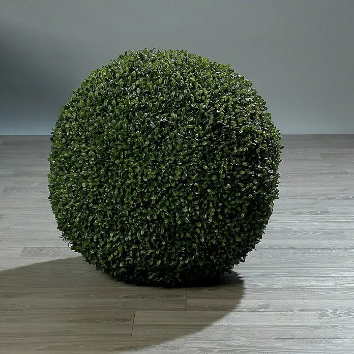 Kunstpflanze Buchskugel - Durchmesser: 30 cm, Kunststoff, Grün - Nahaufnahme einer grünen Buchsbaumkugel auf einem grauen Holzboden, die eine ruhige und natürliche Atmosphäre ausstrahlt.