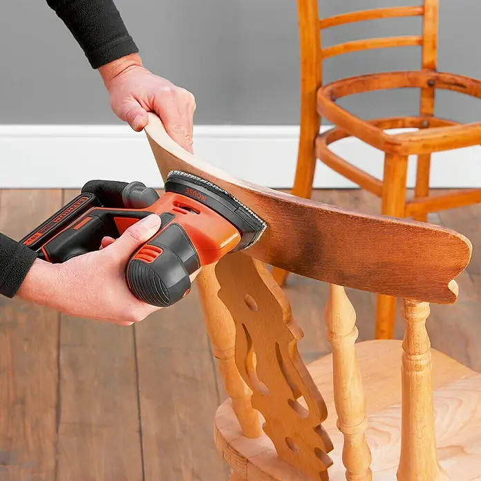 Black+Decker 18V PowerConnect Lijadora delta de batería BDCDS18N-XJ - 18 V, Iones de litio, Sin batería, 24.000 r.p.m. - Una lijadora de detalles BLACK+DECKER Mouse se utiliza para quitar pintura de una silla de madera. La herramienta es roja y negra.