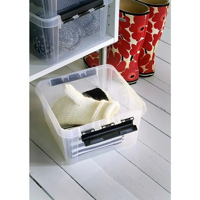 SmartStore Aufbewahrungsbox Classic 7 - L x B x H: 28 x 28 x 17 cm, Kunststoff, Transparent - Klarsichtbox mit schwarzem Verschluss, gefüllt mit Kleidung, steht auf einem weißen Holzboden. Daneben stehen bunte Gummistiefel.