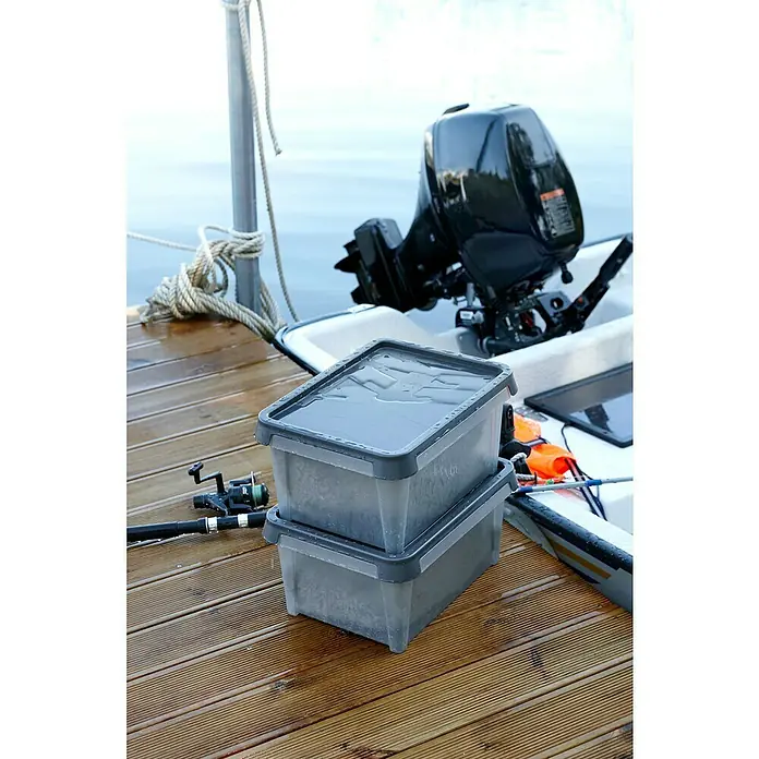 SmartStore Aufbewahrungsbox Dry 34 - 34 l, Lebensmittelecht, Wasserdicht, Stapelbar - Zwei graue, wassergefüllte Aufbewahrungsbehälter stehen auf einem Bootssteg neben einer Angelrute und einem Motorboot. Praktische Behälter für Angelausrüstung.