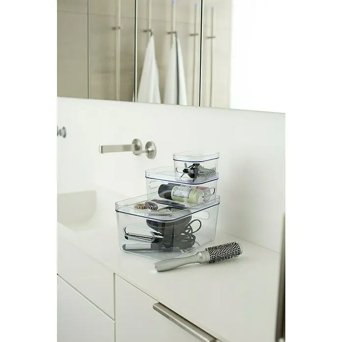 SmartStore Aufbewahrungsbox Compact - L x B x H: 20 x 14 x 7,5 cm, Kunststoff, Transparent - Klare Aufbewahrungsboxen auf einem weißen Waschtisch, die Badutensilien wie Haarbürsten und Haarprodukte ordentlich verstauen.
