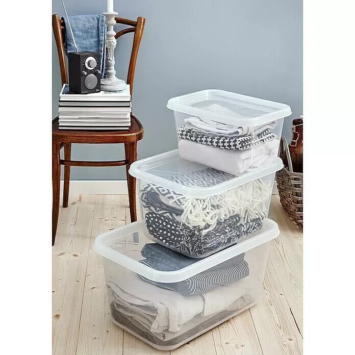 SmartStore Aufbewahrungsbox Basic S - L x B x H: 38 x 27 x 20 cm, 11 l, Mit Deckel - Gestapelte transparente Kunststoff-Aufbewahrungsboxen mit Deckel, gefüllt mit Textilien, auf Holzfußboden.