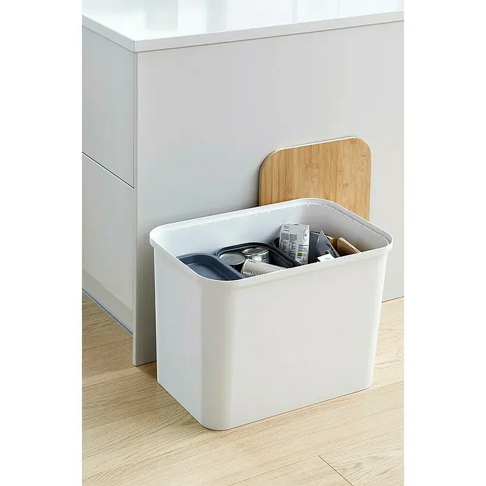 SmartStore Collect Mülltrennsystem - 76 l, Kunststoff, Weiß - Aufnahme eines weißen Abfalltrennsystems neben einem Küchenschrank, das mit Wertstoffen gefüllt ist, und einem Schneidebrett aus Bambus.