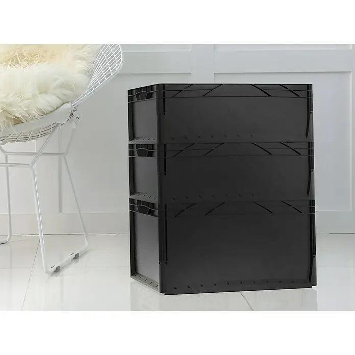 Surplus Systems Eurobox - L x B x H: 60 x 40 x 32 cm, Kunststoff, Schwarz - Ein schwarzer, stapelbarer Kunststoffbehälter steht neben einem weißen Drahtstuhl mit einem weichen Fellkissen.