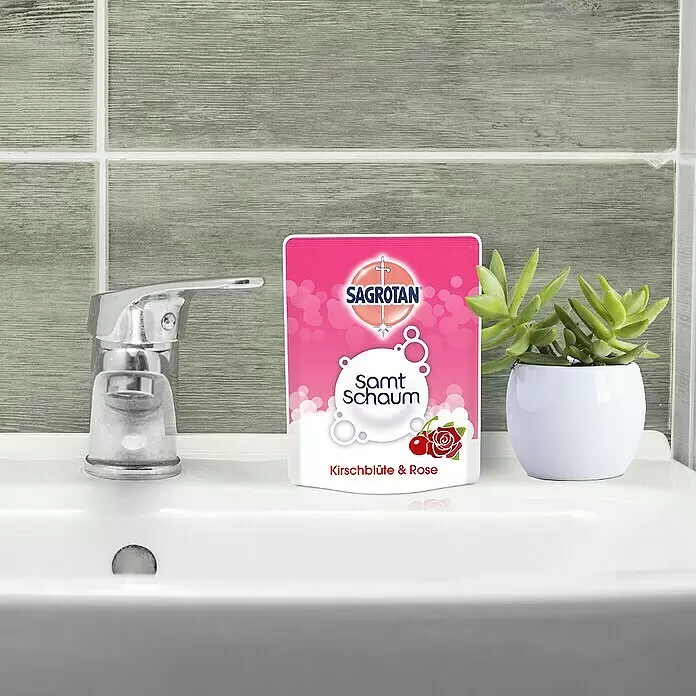 Sagrotan Reinigungsschaum Samt-Schaum Nachfüller - Kirschblüte & Rose, 250 ml - Pinkfarbener Sagrotan Flüssigseifen-Nachfüllbeutel (Kirschblüte & Rose) auf einem Waschbecken.