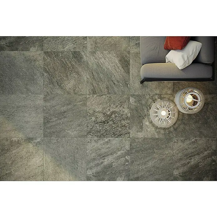 Atlas Concorde Solution Regent Terrassenfliese Grey - 60 x 60 x 2 cm, Grau, Matt - Nahaufnahme von strukturierten grauen Bodenfliesen, die ein modernes, elegantes Design mit einem Sofa und dekorativen Laternen zeigen.