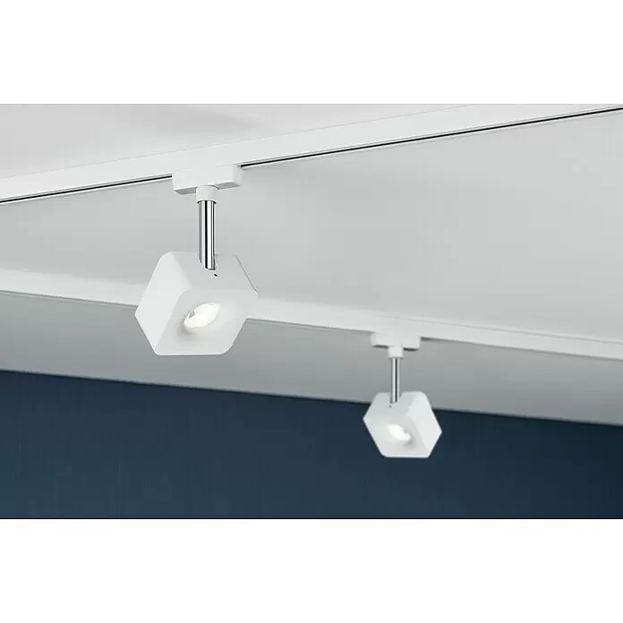 Paulmann URail LED-Spot Cube - 8 W, Weiß, Chrom, L x B x H: 47 x 77 x 165 mm - Zwei weiße sechseckige Stromschienenstrahler mit Chromstielen, an einer weißen Deckenstromschiene montiert, beleuchten eine dunkelblaue Wand.