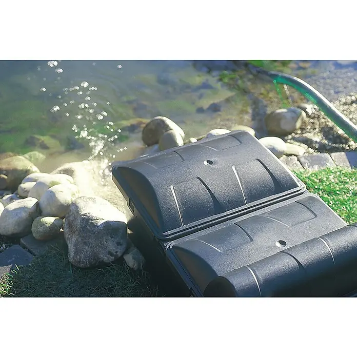 Neptun Premium Durchlauffilter Premium - 70 W, Teichgröße: 15 m³, Leistung UVC-Klärer: 14 W - Nahaufnahme einer schwarzen Teichfilteranlage am Ufer, mit Blick auf das Wasser und die Umgebung.