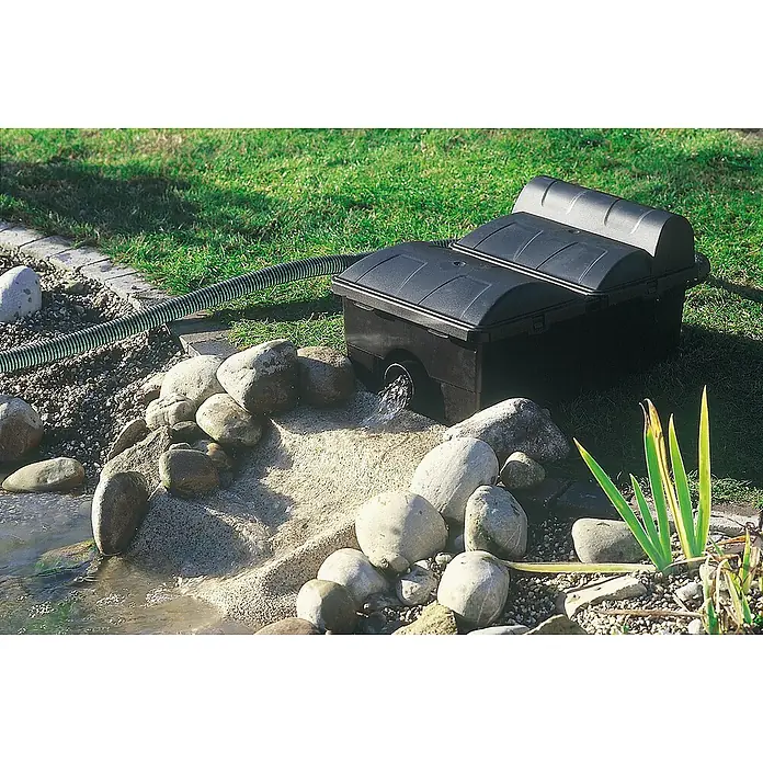 Neptun Premium Durchlauffilter Premium - 70 W, Teichgröße: 15 m³, Leistung UVC-Klärer: 14 W - Teichfilter-System mit zwei schwarzen Boxen neben einem kleinen Teich, umgeben von Steinen und Grün. Inklusive Schlauchanschluss.