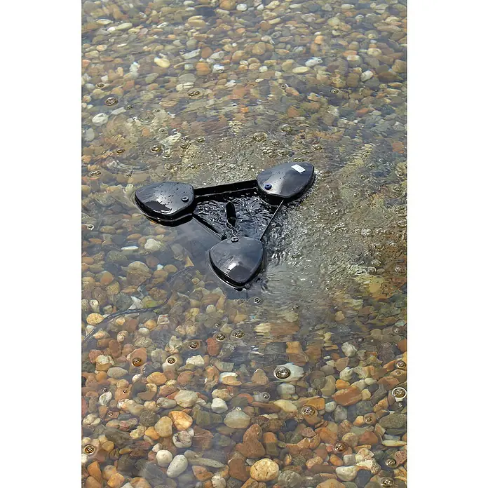 Oase Skimmer SwimSkim 25 - Leistungsaufnahme: 40 W, Fördermenge pro Std.: 2.500 l - Ein schwarzes, dreieckiges Gadget schwimmt auf einem Flussbett, das mit kleinen Steinen übersät ist. Das Gerät wirkt neu und modern.