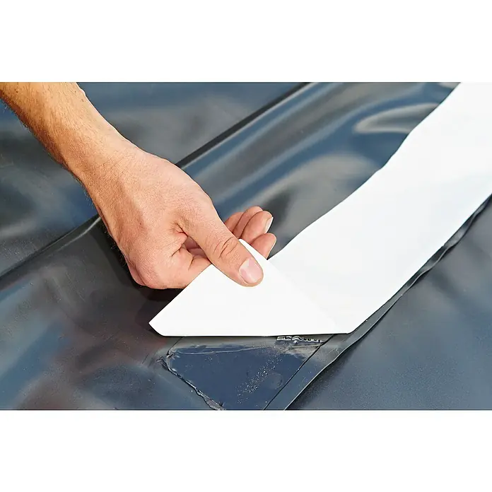 Oase Nahtfügeband FixoFol - 600 x 7 cm, Geeignet für: EPDM-Teichfolie - Reparatur einer beschädigten Oberfläche mit einem weißen Klebeband, das von einer Hand aufgetragen wird. Das Band deckt den Riss im Material ab.