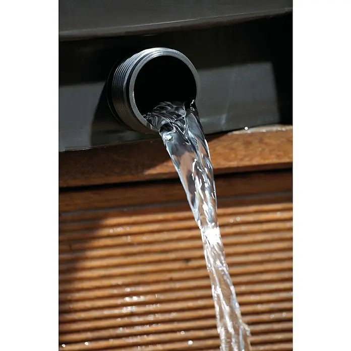 Oase BioSmart Durchlauffilter Set 7000 - 40 W, Teichgröße: 7 m³ - Nahaufnahme eines Abflussrohrs, aus dem Wasser auf eine hölzerne Oberfläche fließt.