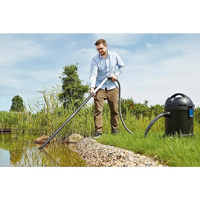 Oase Teichschlammsauger PondoVac Classic - 1.400 W, Tankvolumen: 27 l - Ein Mann benutzt einen Teichsauger, um einen Gartenteich zu reinigen. Der schwarze Teichsauger steht auf dem Rasen und saugt Schmutz aus dem Wasser.