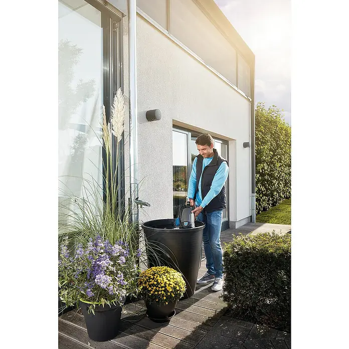 Oase ProMax Rain Regenfasspumpe ProMax Rain - 370 W, 4.000 l/h - Ein Mann benutzt eine Pumpe, um Wasser aus einem Regenfass zu befördern. Die Pumpe ist kompakt und ideal für die Gartenarbeit.