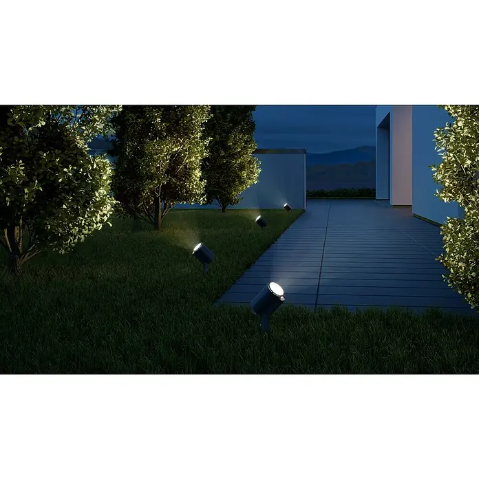 Steinel LED-Strahler Spot Garden SC anthrazit - 7,9 W, 512 lm, 3.000 K, L x B x H: 14 x 6,9 x 36,9 cm, IP44 - Das Bild zeigt eine Außenansicht mit Gartenleuchten, die die Bäume und den Weg beleuchten. Die Leuchten sind ein dezenter Blickfang im dunklen Garten.