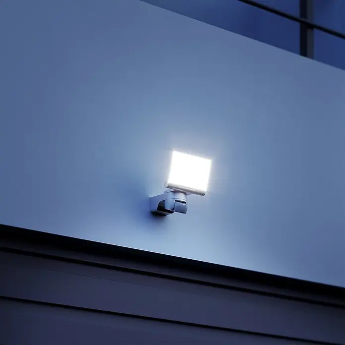 Steinel Aplique exterior LED con sensor XLED Home 2 - 13,7 W, L x An x Al: 16,1 x 18 x 21,8 cm, Negro, Blanco cálido - Primer plano de una luz exterior cuadrada y brillante en una pared, que combina seguridad con estilo.