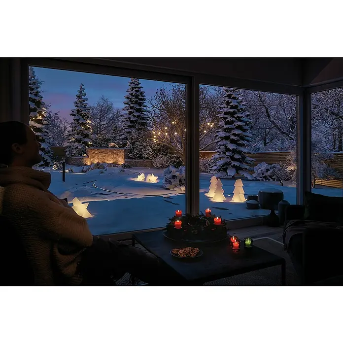 Paulmann Plug & Shine LED-Dekoleuchte Star - Weiß, L x B x H: 10 x 40 x 40 cm - Eine stimmungsvolle Winterlandschaft mit beleuchteten Dekorationen im Garten, betrachtet durch ein Fenster mit Adventskranz und Kerzen im Vordergrund.