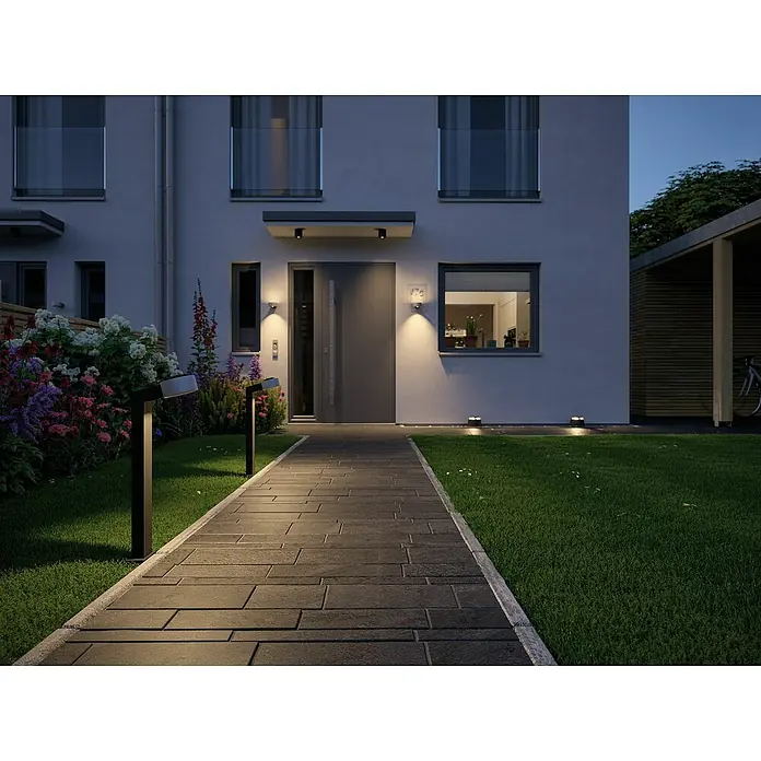 Paulmann Plug & Shine LED-Außenleuchte - 6 W, Warmweiß, IP67, Ø x H: 19,3 x 15,5 cm - Eine moderne Hausfassade mit einer grauen Tür, flankiert von stilvollen Außenleuchten und einem gepflasterten Weg, der zum Eingang führt.