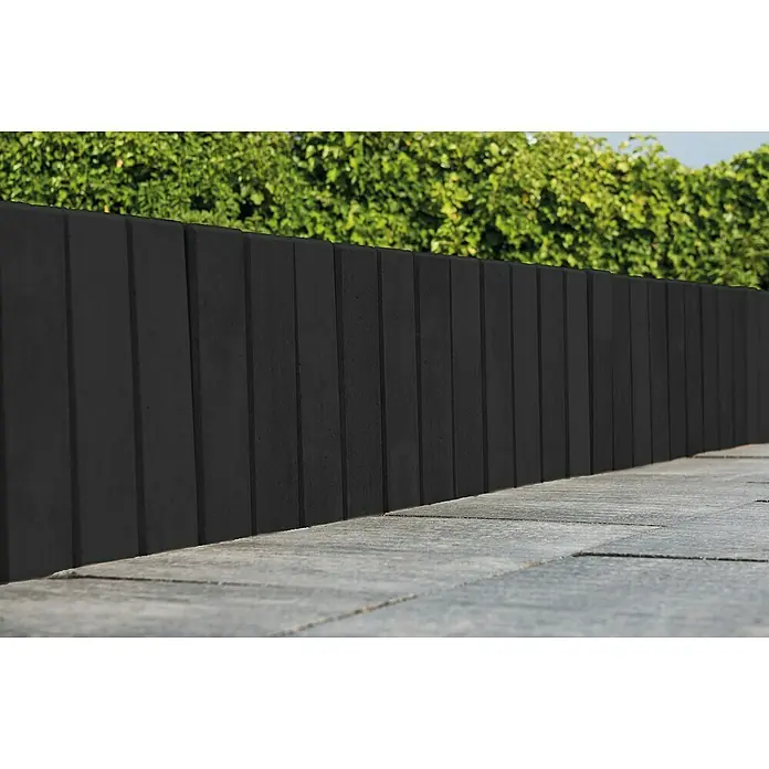 Diephaus Palisade / Mauerstein Laredo - 40 x 10 x 10 cm, Basalt, Beton - Eine moderne, graue Betonmauer dient als stilvolle Grundstücksbegrenzung und bietet Privatsphäre mit dem frischen Grün im Hintergrund.