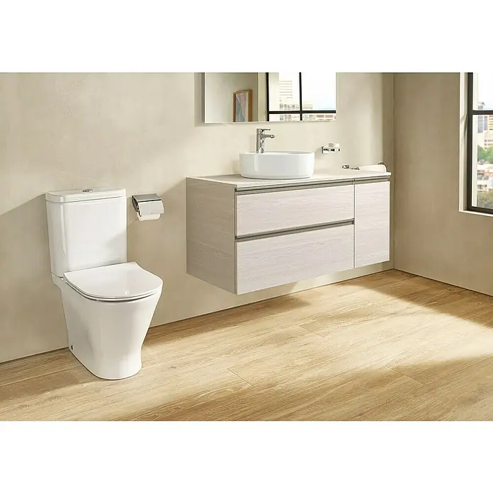 Roca Pack de WC adosado Heracles - Sin borde de descarga, Salida dual, Blanco - Un baño moderno con un inodoro blanco y un tocador con textura de madera. Diseño elegante para un espacio de baño confortable.