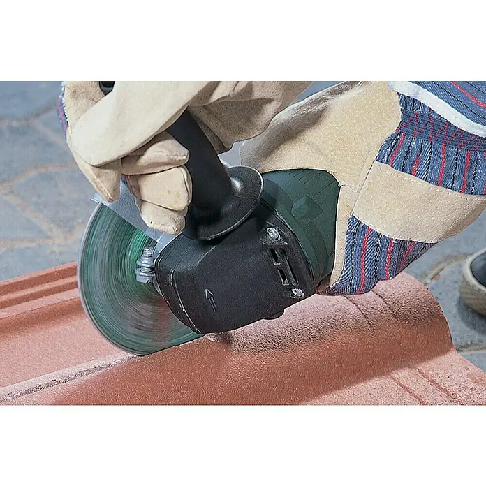 Wolfcraft Trennscheibe - 115 mm, 1 Stk., Geeignet für: Stein, Gekröpft - Eine Winkelschleifmaschine schneidet durch ein Ziegel, getragen von Händen in Schutzhandschuhen.