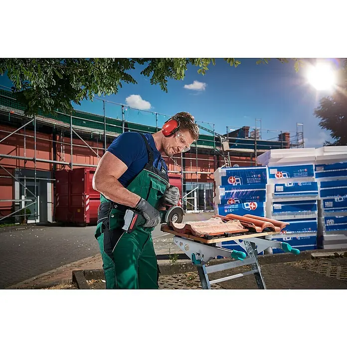 Wolfcraft Trennscheibe - 115 mm, 1 Stk., Geeignet für: Stein, Gekröpft - Ein Handwerker schneidet Ziegel mit einer Trennscheibe auf einer Werkbank, mit Schutzausrüstung, vor Baustellenzubehör.