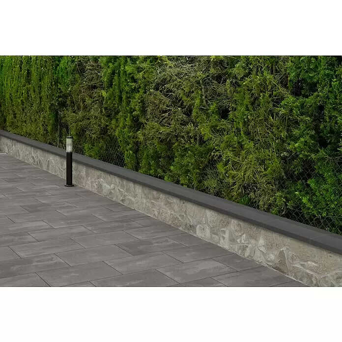 Mauerabdeckplatte Satteldach - Anthrazit, 50 x 25 cm, Beton - Graue rechteckige Pflastersteine neben einer Steinmauer mit dunkler Abdeckung.