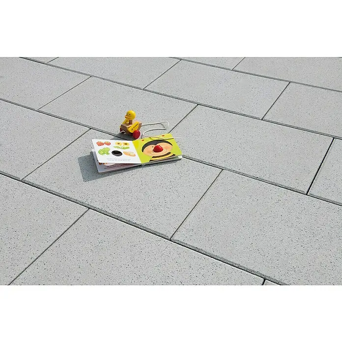 Diephaus Terrassenplatte Norfolg - 60 x 40 x 4 cm, Quarz, Beton - Ein Bilderbuch mit einem gelben Spielzeug auf einem grauen Steinpflaster. Das Buch ist offen und zeigt eine farbenfrohe Illustration.