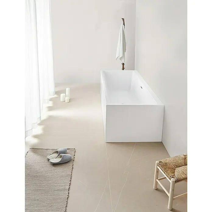 Camargue Freistehende Badewanne Torino Cube - L x B: 180 x 80 cm, Sanitäracryl, Weiß - Ein minimalistisches Badezimmer mit einer modernen, rechteckigen Badewanne, einem hellen Teppich und sanftem Tageslicht.