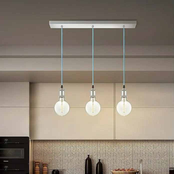 Home Sweet Home Textilkabel Meterware Online - Hellblau, 3, 0,75 mm² - Diese Aufnahme zeigt eine moderne Pendelleuchte mit drei Edison-Glühbirnen an blauen Kabeln, die von einer rechteckigen Halterung herabhängen.