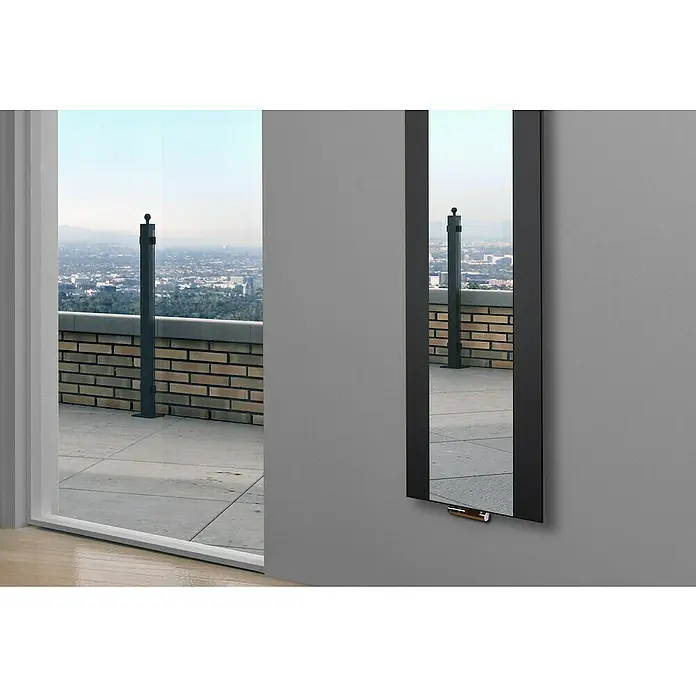 Szagato Designheizkörper Singapur - B x H: 470 x 1.800 mm, Schwarz, Mit 2 Handtuchhalter (50 mm) - Ein schlanker, schwarzer Spiegel hängt an einer grauen Wand und reflektiert einen Balkon mit Stadtblick. Das moderne Design ergänzt die urbane Umgebung.