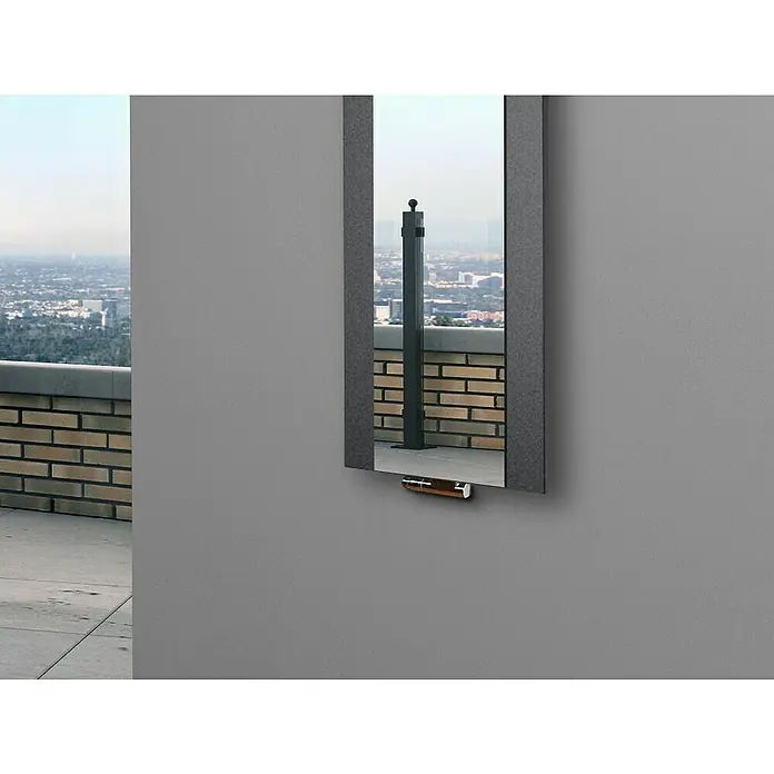 Szagato Designheizkörper Singapur - B x H: 470 x 1.200 mm, Wärmeleistung bei Vorlauftemperatur von 75 °C (D: 50): 799 W, Moonstone-Grau, Mit 1 Handtuchhalter (50 mm) - Ein schmaler Spiegel an einer Wand spiegelt eine Ziegelmauer und einen grauen Pfosten, der die urbane Landschaft widerspiegelt.