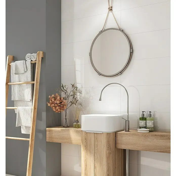 Revestimiento de pared Blanc - 90 x 30 cm, Blanco, Espesor: 8 mm, Brillante, Rectificado - Un baño con un tocador de madera clara, un espejo redondo y toallas blancas en una escalera. El diseño combina rústico con elementos modernos.