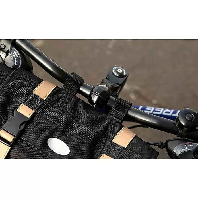 Lenkertasche - Volumen: 10 l, Schwarz - Schwarze Fahrrad-Lenkertasche mit beigen Riemen und schwarzer Schnalle, an einem Fahrradlenker neben einer Klingel und Gangschaltung befestigt.