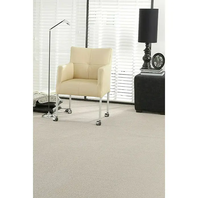 Teppichboden Meterware Linda - Breite: 400 cm, Velours, 100 % Polypropylen, Hellbeige - Beige Bürostuhl mit Armlehnen und Chromfüßen auf Teppich vor einem Fenster mit Jalousien. Elegantes Design für Büro oder Arbeitszimmer.